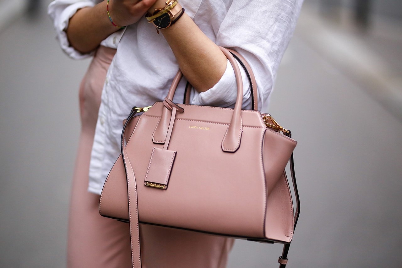 Sarah Benziane, fashion blogger Les Colonnes de Sarah, wears a New Look white shirt, New Look pink pants, Zara white shoes with wooden heels, sunglasses, and an Ali Express pink bag, on March 18, 2017 in Paris, France